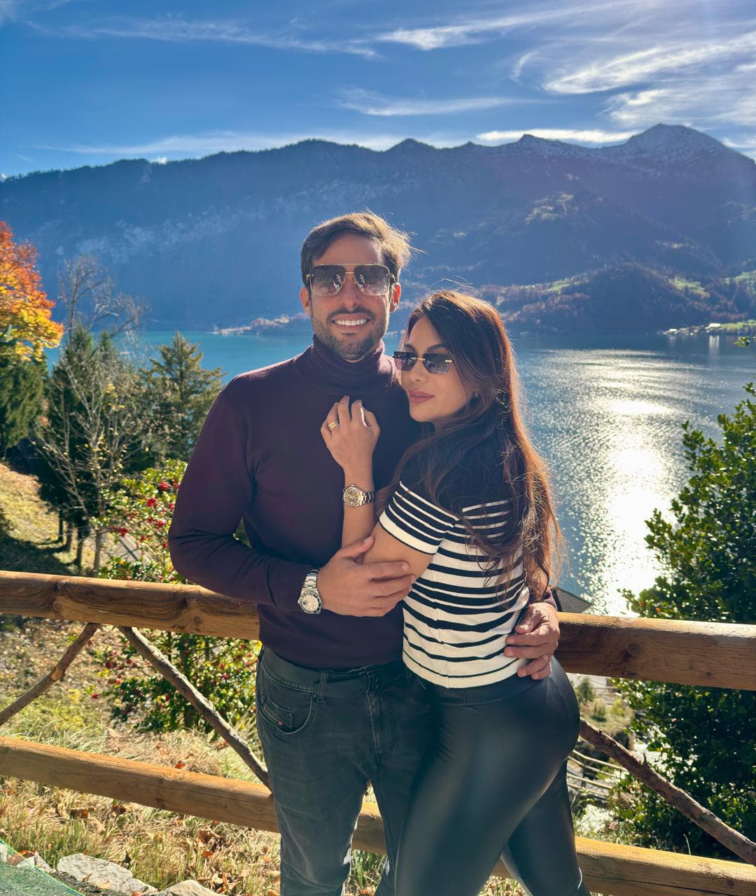 Gina e José Carlos abraçados diante de um lago cercado por montanhas.